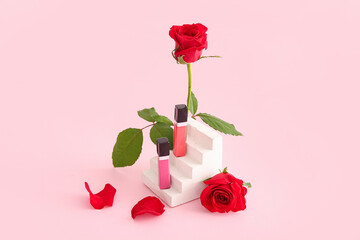 Composition with stylish lipsticks and beautiful red rose flowers on pink background