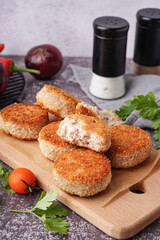 Wooden board of tasty meat cutlets on grey background