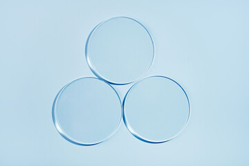 Three empty petri dishes on blue background. Mockup for cosmetic product sample
