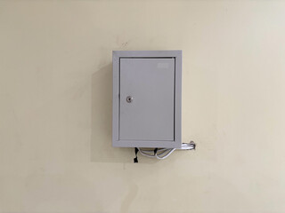 A small gray metal utility box mounted on a plain beige wall