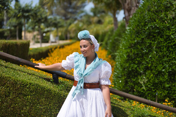 Young, beautiful, blonde woman in typical Andalusian flamenco costume for a pilgrimage in white...