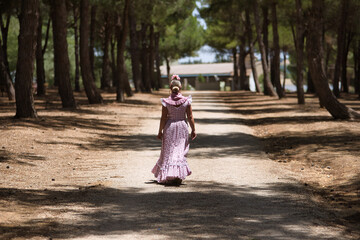Young woman, beautiful, blonde, with typical Andalusian flamenco costume to go on pilgrimage with...