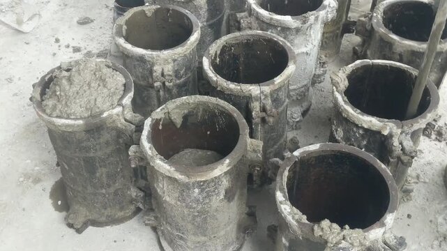 Technician preparing cylindrical concrete test samples in molds for laboratory strength testing at a construction site.