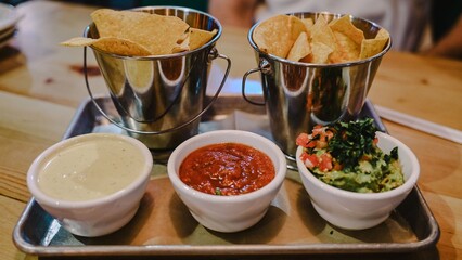 Tortilla chips with dips on a tray.