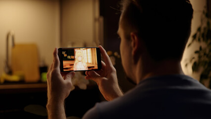 Watching Japanese anime with cute anime girls on smartphone with kitchen in background