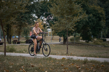 Fototapeta premium Young beautiful woman riding a bicycle in the park. Active people. Outdoors