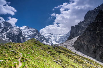 An old glacier moraine covered with green grass and rhododendron shrubs in Mizhirgi valley near 