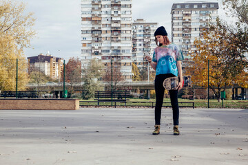 Young woman with skateboard looking at cell phone