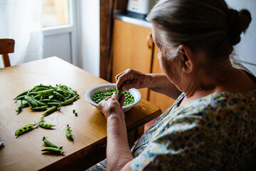 Woman Shelling Fresh Green Peas at a Wooden Table