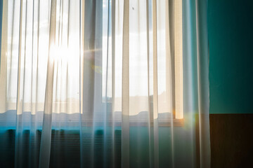Obraz premium Sunlight Streaming Through Sheer Curtains Illuminating an Interior Room With Blue Wall