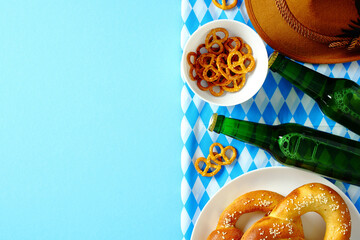 Oktoberfest celebration concept. Top view salted pretzels, green beer bottles, Bavarian hat, and...