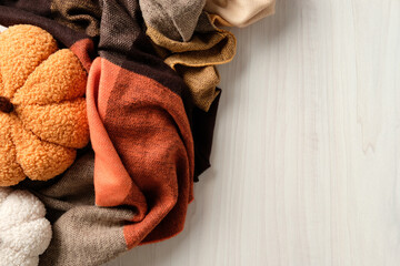 Soft plush pumpkin on cozy plaid in warm autumn tones. Minimalist seasonal flatlay evoking comfort,...