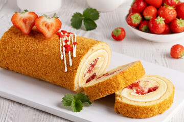 Delicious strawberry roll cake served on a wooden board with fresh strawberries in a white bowl in...