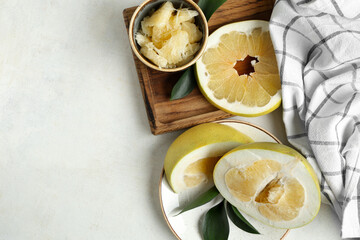 Wooden board and plate with cut fresh pomelo fruits on white background