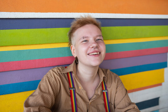 Happy non-binary person in front of multi colored wall