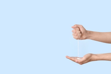 Male hands with pouring sand on blue background. Time concept