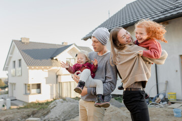 Mother and father carrying daughters outside house