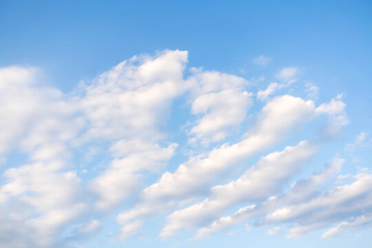 Soft white clouds are gently drifting across a bright blue sky, creating a serene and tranquil atmosphere, inviting viewers to appreciate the beauty of nature and the vastness of the sky