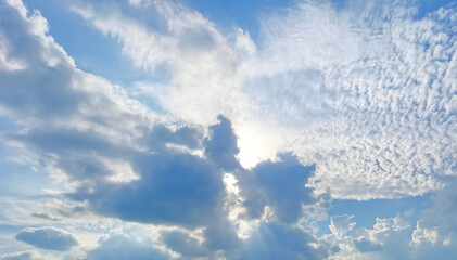 Dramatic cloud formations create a stunning visual display as sunlight breaks through, illuminating the vibrant blue sky and casting soft shadows across the landscape, evoking a sense of tranquility
