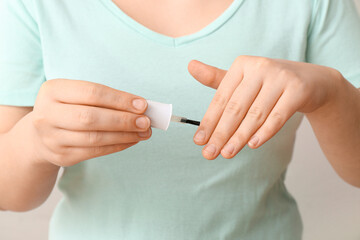 Woman applying cuticle oil with brush on white background, closeup