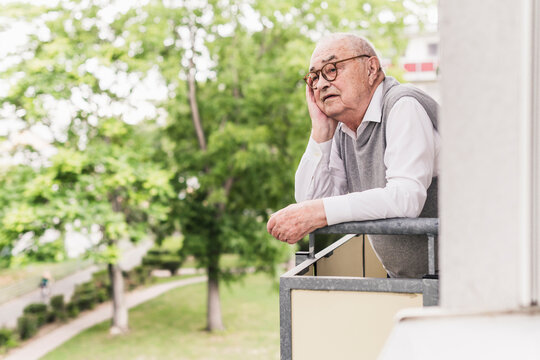 Portrait of senior man standing on balcony looking at distance