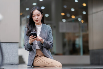 Businesswoman using smartphone and smartwatch outdoors