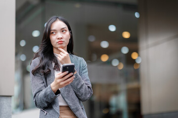 Businesswoman thinking while reading news on smartphone in urban setting