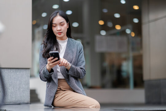 Businesswoman using smartphone and smartwatch outdoors