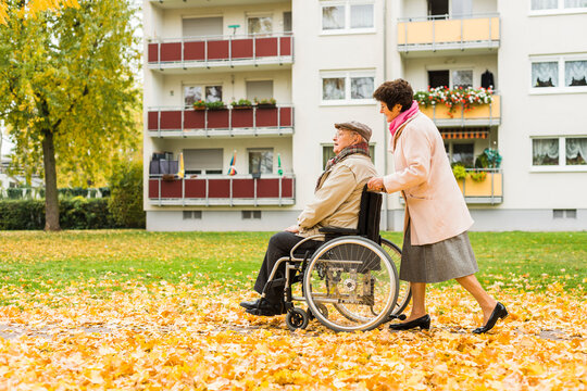 Senior woman pushing husband in wheelchair