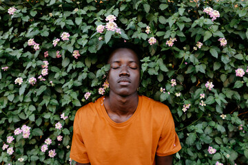 Young man with eyes closed relaxing amidst plants