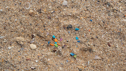 Macro shot of micro plastic particles in the sand at the beach. Concept of plastic pollution and water contamination with microplastics.