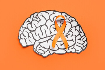 Paper brain and orange ribbon on color background. Multiple Sclerosis Awareness Month