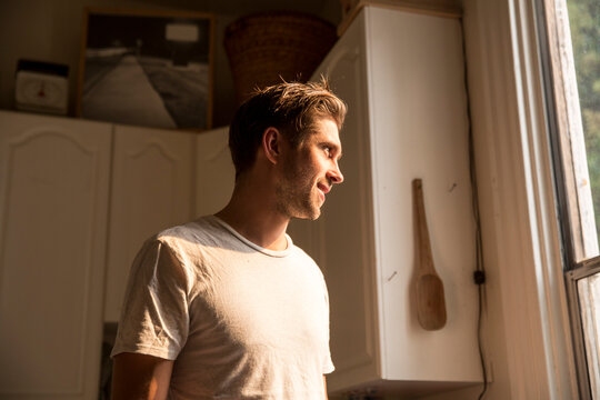 Smiling man at home looking out of window