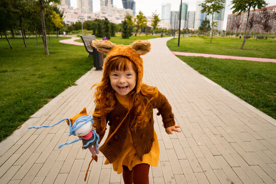 Cheerful girl with doll running in park