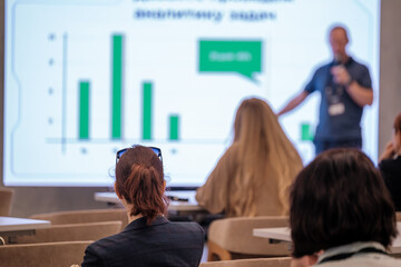 People attending business presentation with presenter explaining graphs on display board