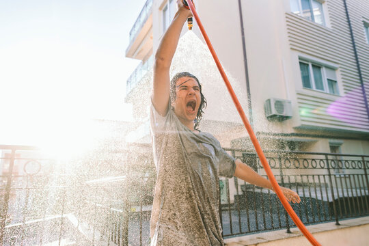 Teenage boy enjoying refreshing water spray outdoors on a sunny summer day