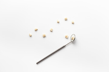 Many human teeth crown for dental implantation with dental mirror on white background. Professional Dentist tools, top view