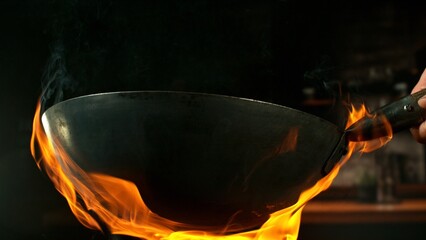 Freeze Motion of Empty Wok Pan with Flames Burning Around. Kitchen Interior on Background.