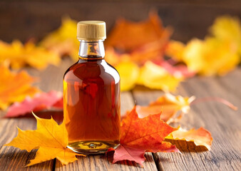 Maple syrup - small bottle with maple leaves around, wooden table