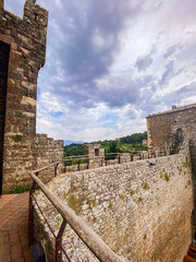 Montalcino Fortress rising above rolling Tuscan hills, weathered stone walls silhouetted against...