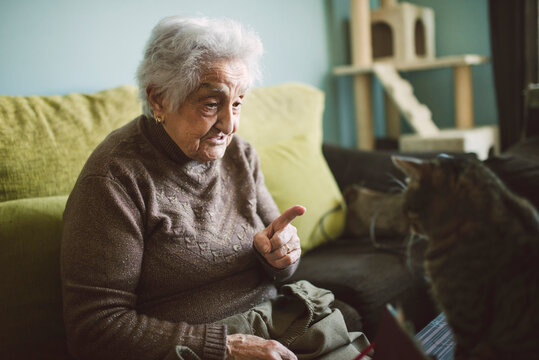 Senior woman sitting on the couch scolding her cat