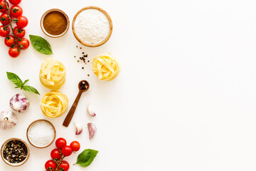 Fettuccine with ingredients for cooking pasta - tomatoes and basil with garlic - on a white background, top view. Flat lay