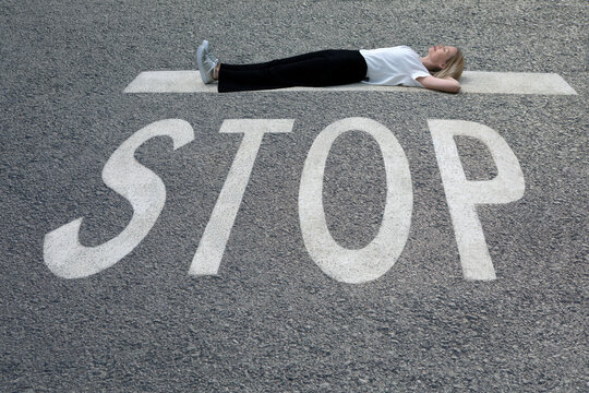 Woman with hands behind head lying down on road at STOP sign