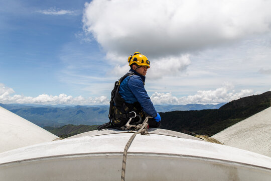 Engineer performing maintenance on top of a wind turbine nacelle outdoors
