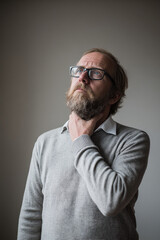 Fototapeta premium man with thoughtful expression places his palm on his neck conveying sense of tension
