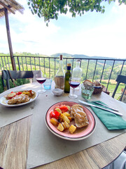 Savoring rustic Tuscan lunch with regional wine, overlooking rolling countryside from medieval...