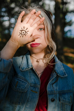 Young woman showing eye sign tattoo on her hand