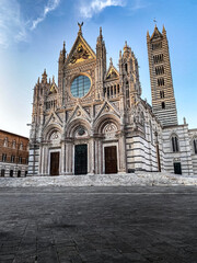 Siena Cathedral facade and bell tower rising majestically on Piazza del Duomo in Siena, Tuscany, Italy, under a blue sky