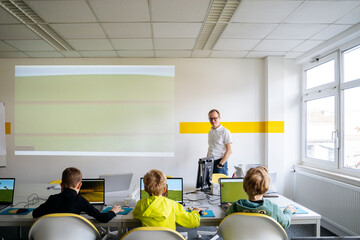 Professor teaching boys in computer classroom at school