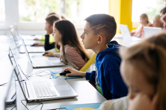 Dedicated boy using laptop learning computer coding in classroom